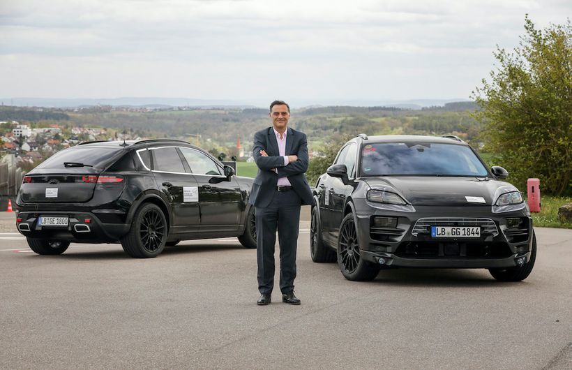 Porsche Macan electric prototypes, disguised test cars front and rear static with chief engineer Michael Steiner