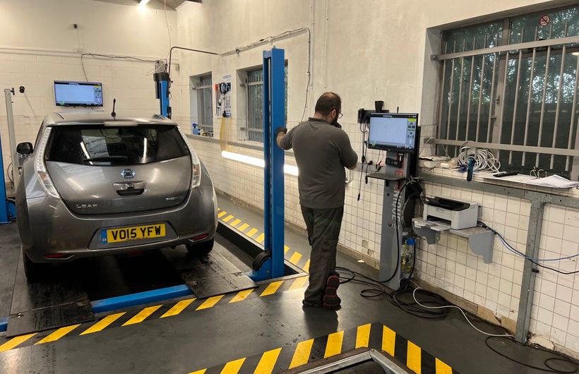 Grey 2015 Nissan Leaf in MoT test bay on ramps, with tester checking data on computer screen
